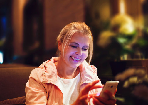 Pretty blonde woman looking at smartphone in cafe