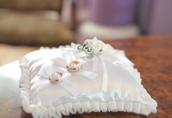 wedding rings on satin cushion with decor