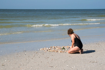 Fototapeta na wymiar Nice photo of a woman sorting through seashells on a sandy beach on the Gulf of Mexico.