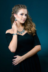 Fototapeta na wymiar Beautiful young model with earrings necklace and ring on dark background