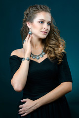 Beautiful woman showing earrings necklace and ring on dark background