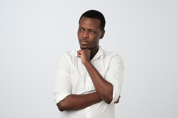 African american man looking aside with thoughtful and skeptical expression, trying to remember...
