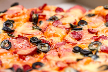 Pizza with salami, cheese and black olives. Selective focus. Close up.	
