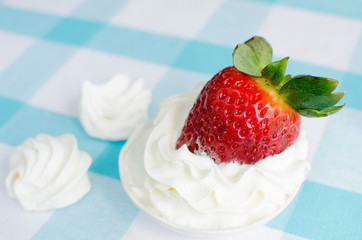 Fresh strawberries with cream on a blue tablecloth and meringue