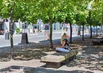Young woman sitting on bench in city park.