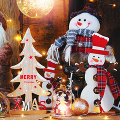 Santa clouse dolls and christmas decorations on dark rustic wooden backgroud with light garland.