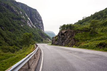 Mountain road. Landscape with rocks, sky with clouds and beautiful asphalt road in the evening in summer. Highway in mountains. Sweden