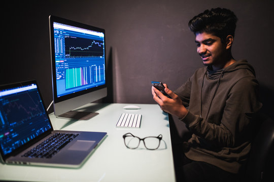 Serious indian trader using mobile phone app on smartphone for checking stock trading data analysis concept. 