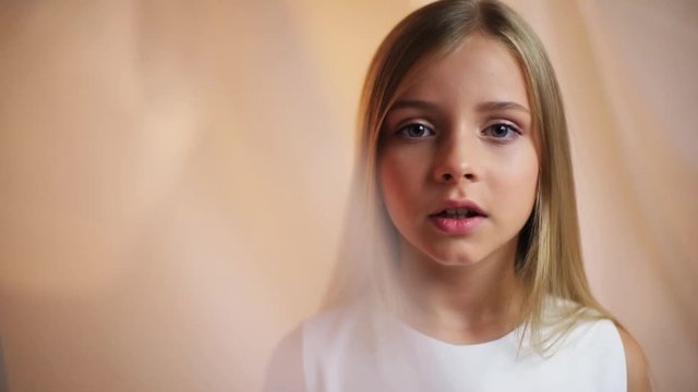 Face little girl with a make-up looks at camera feel shock talk angry serious sad stand indoors cute young attractive blonde hair beautiful caucasian female pretty portrait close up slow motion