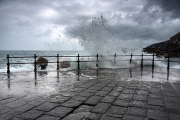 Storm on Amalfi coast. Wave surging on the pier and stone pavement 