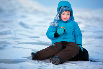 Cute little boy having a picnic on winter beach