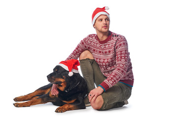 A young man wearing Santa hat sitting with his purebred dog.