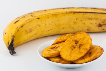 Fried half ripe plantain slices isolated on white background