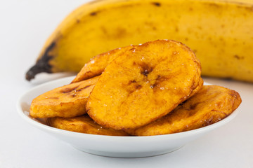 Fried half ripe plantain slices isolated on white background