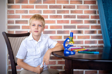 Little boy working with microscope for studying microbes