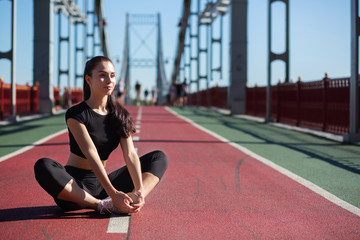 Awesome fitness model doing stretching and preparing to running at the bridge. Space for text