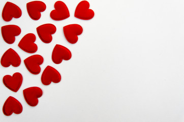 Red heart shaped confetti background or corner border over white. Top view, flat lay