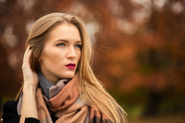 Closeup shot of elegant blonde model with red lips wering fashionable warm apparel. Empty space