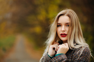 Naklejka premium Stylish dressed lovely model with long hair posing at the autumn street. Empty space