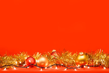 Christmas background  with tinsel baubles and lights on red