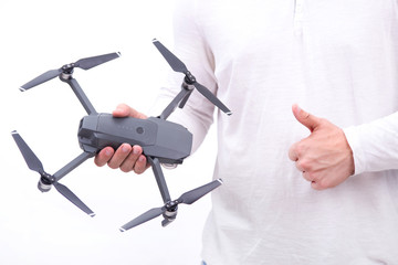 A young man holds a flying drone in his hands on a white background. Theme selling and buying drone