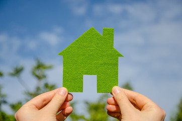 Hands holding eco house icon concept on the blue sky background 