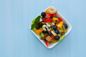 Bowl of healthy fresh fruit salad on wooden background.