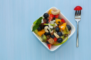 Bowl of healthy fresh fruit salad on wooden background.