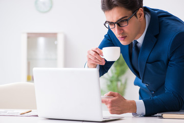 Young handsome businessman drinking coffee in the office 