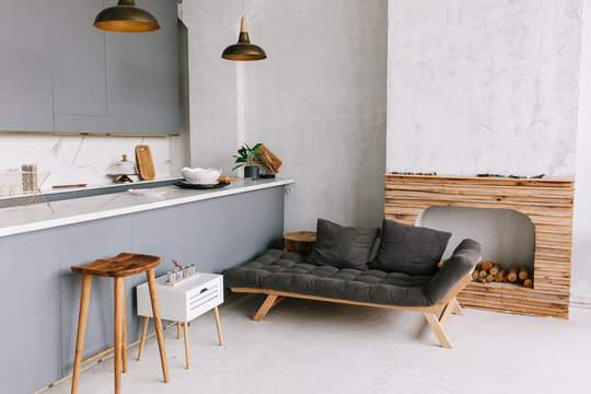 Interior of the modern loft kitchen-studio in the apartment. Room, furniture, sofa near wooden fireplace