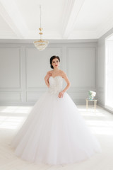 Young brunette bride in white luxury wedding dress. Classic studio interior, full-lenght portrait