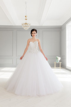 Young brunette bride in white luxury wedding dress. Classic studio interior, full-lenght portrait
