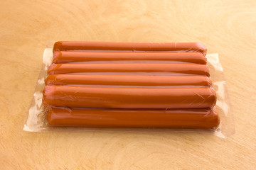 Sausages vacuum packed on a wooden surface. A bundle of sausages from the store on a wooden table.