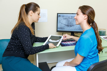 Fototapeta premium Young woman Dentists and woman patient discussing the x-ray photograph on computer treatment discussion