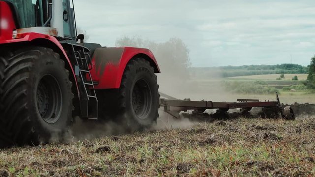Farmer in tractor prepares land with seedbed cultivator in early spring season of agricultural works at farmlands