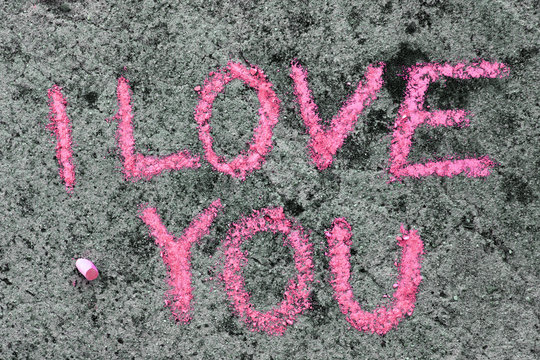 Colorful chalk drawing on asphalt: Pink words I LOVE YOU