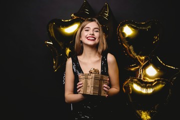 Beautiful happy woman with gift box at celebration party. Birthday or New Year eve celebrating...
