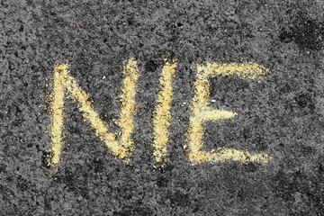 Słowo NIE napisane żółtą kredą na betonie. Bunt dziecka lub asertywność.  - obrazy, fototapety, plakaty