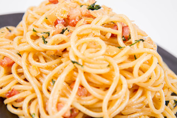 Spaghetti Carbonara with some parsley on a black plate on a white background