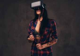 Tattooed girl wearing a red unbuttoned checked shirt wearing a VR headset.