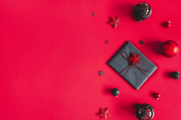 Christmas composition. Christmas gift, red and black decorations on red background. Flat lay, top view, copy space