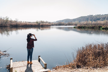 Young brunette woman on a jetty with binoculars