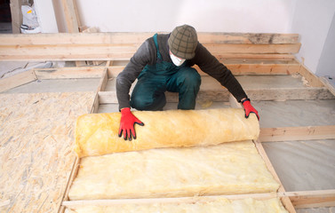 Work composed of mineral wool insulation in the floor, floor heating insulation , warm house, eco-friendly insulation, a builder at work