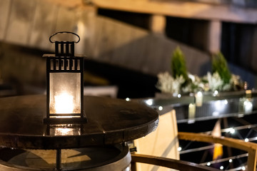 Vintage iron christmas lantern with burning candle light on wooden table barrel on restaurant terrace on water in Prague