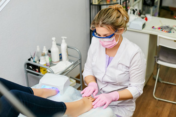 Work in a beauty salon. The girl does the work of caring for her feet.