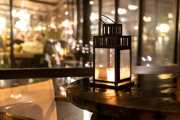 Vintage iron christmas lantern with burning candle light on wooden table barrel on restaurant terrace on water in Prague.