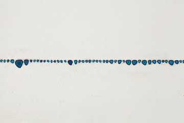 Blue paint drops on white surface background. The surface of the walls are whitewashed with lime. Horizontal blue stripe on grey background. Pattern of blue elements on white background.