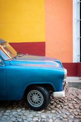 Vintage american car parked with colored wall im background 