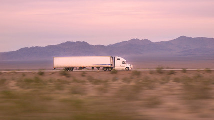 CLOSE UP: Freight semi truck driving and transporting goods on empty highway - obrazy, fototapety, plakaty