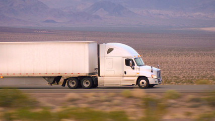 CLOSE UP: Freight semi truck driving and transporting goods on empty highway © helivideo